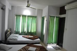 a bedroom with two beds and green curtains at Hotel Shams Plaza in Cox's Bazar