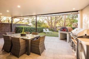 a patio with a table and chairs and a kitchen at 'Azure' Beachside Resort Escape for Groups in Marybrook