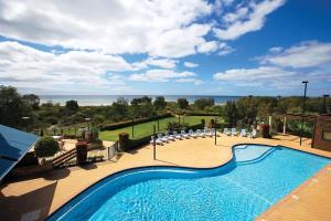 a swimming pool with chairs and a view of the ocean at 'Azure' Beachside Resort Escape for Groups in Marybrook