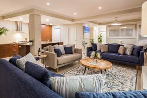 a living room with blue couches and a table at 'Azure' Beachside Resort Escape for Groups in Marybrook