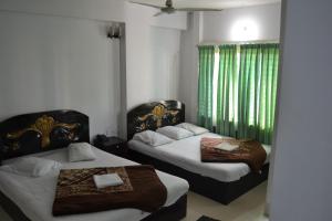 1 dormitorio con 2 camas y cortina verde en Hotel Shams Plaza, en Cox's Bazar