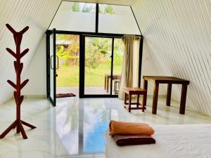 a room with a bed and a table and windows at Marina Safari Resort Udawalawe in Udawalawe