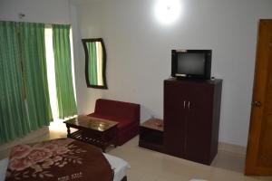 a living room with a tv on a cabinet and a chair at Hotel Shams Plaza in Cox's Bazar