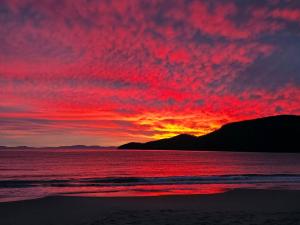 a sunset on the beach with a red sky at Bruny Island Holiday Park in Adventure Bay
