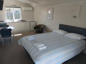 a bedroom with a large bed with towels on it at Harbourside Holiday Park in Whitianga +43 photos