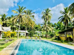 a pool in front of a house with palm trees at Marina Safari Resort Udawalawe in Udawalawe