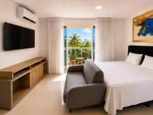 a bedroom with a bed and a couch and a television at The Expression Building - Setor Bueno - THP in Goiânia