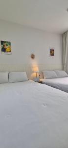 a bedroom with two white beds and a lamp at 1&2stayㅡH in Tongdaegu-yŏk