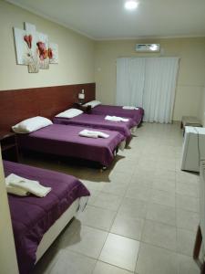 a row of beds in a room with purple sheets at Hotel Don Oresttes in La Carrera