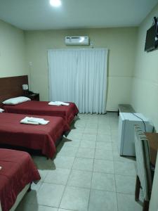 a hotel room with three beds with red sheets at Hotel Don Oresttes in La Carrera