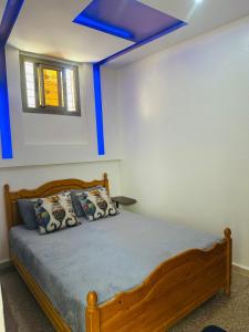 a bedroom with a wooden bed with a blue ceiling at Appartement au centre de TIZNIT in Tiznit