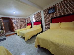 a bedroom with two beds and a brick wall at Hotel Fer in San Juan Teotihuacán