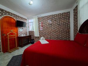 a bedroom with a red bed with a brick wall at Hotel Fer in San Juan Teotihuacán