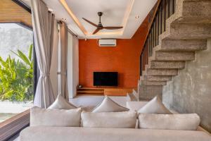 a living room with a couch and a tv at Duality Villas in Ubud