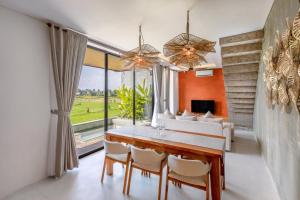 a dining room with a table and chairs and a large window at Duality Villas in Ubud