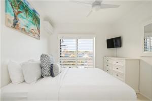 a white bedroom with a white bed and a window at Riverfront 2BR Apt with Views, Balcony & Parking in Maroochydore