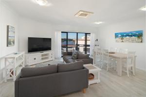 a living room with a couch and a tv and a table at Riverfront 2BR Apt with Views, Balcony & Parking in Maroochydore
