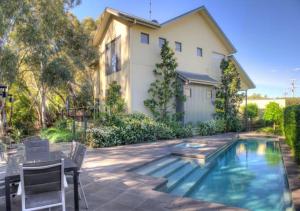 a house with a swimming pool in front of a house at The Gums - Echuca Holiday Homes in Echuca