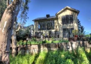 a house with a retaining wall and a tree at The Gums - Echuca Holiday Homes in Echuca