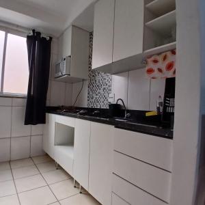 a kitchen with white cabinets and a black counter top at Apartamento Harmonia! in Uberaba
