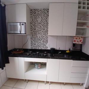 a kitchen with white cabinets and a black counter top at Apartamento Harmonia! in Uberaba