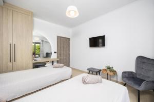 a bedroom with two beds and a chair and a desk at Villa Vatia 2 in Tragaki +20 photos