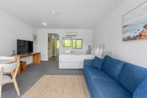 a living room with a blue couch and a bed at Bay View - Green Vista in Lorne