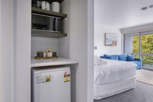 a white room with a bed and a refrigerator at Bay View - Green Vista in Lorne