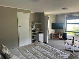 a bedroom with a bed and a flat screen tv at The Pacific Room, Tapeka Point in Russell
