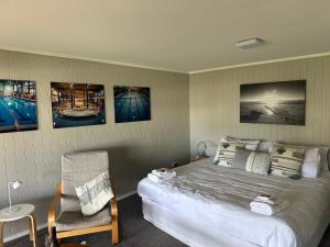 a bedroom with a bed and a chair and pictures on the wall at The Pacific Room, Tapeka Point in Russell