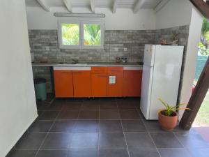 a kitchen with orange cabinets and a white refrigerator at Terakota lodge in Deshaies