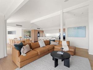 a living room with a brown couch and a table at Eagle Heights - Elevated Oasis with Pool & Sea Views in Dunsborough