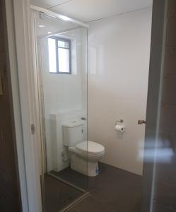 a bathroom with a toilet and a glass shower door at Peppercorn Motel in Clermont +11 photos