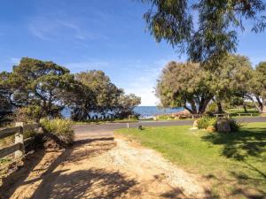 a dirt road with trees and the ocean in the background at Torretta by the Bay in Dunsborough