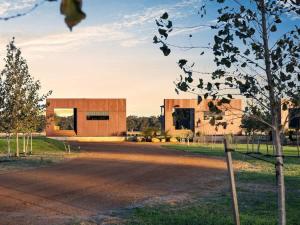 a building in the middle of a field with a tree at Samphire Chalet Tuart - Luxury Amidst Nature in Geographe