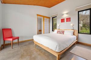 a bedroom with a bed and a red chair at Petra Olive 1 in Yallingup