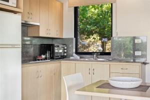 a kitchen with wooden cabinets and a sink and a window at Petra Olive 1 in Yallingup +11 photos