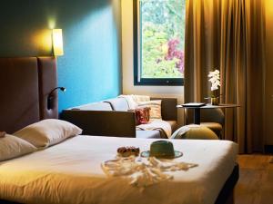 a hotel room with a bed and a couch at Ibis Sarlat Centre in Sarlat-la-Canéda +91 photos