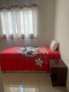 a bed with a red blanket with a flower on it at Prive Familiar e Aconchegante in Paulista