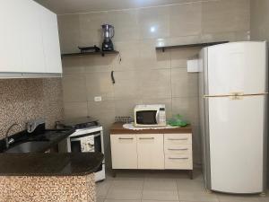 a kitchen with a white refrigerator and a microwave at Prive Familiar e Aconchegante in Paulista