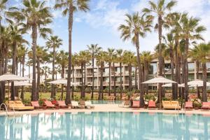 a resort pool with chairs and palm trees at Kimpton Atlantico Algarve by IHG in Albufeira