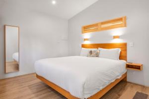 a bedroom with a large white bed and a mirror at Petra Olive 4 in Yallingup
