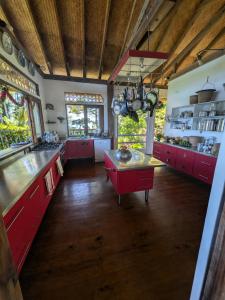 a large kitchen with red cabinets and a table at Fare Tihi Moana in Tahu-Naoe +5 photos