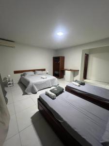 a bedroom with two beds and a table in it at Pousada Boa Praia Guriri in São Mateus