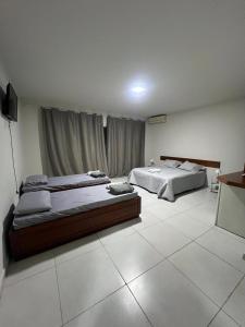 a bedroom with two beds and a television in it at Pousada Boa Praia Guriri in São Mateus