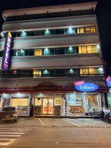 a building on a street at night with cars parked in front at Hotel Tiffany - Laoag in Laoag