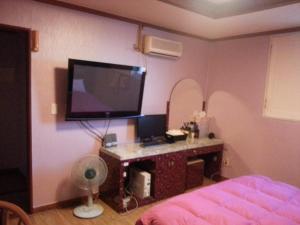 a bedroom with a tv and a desk with a fan at Prince Hotel in Gwangju