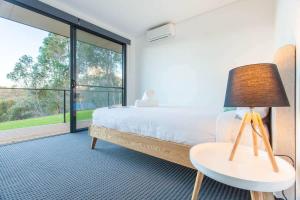 a bedroom with a bed and a table with a lamp at Lake View - Contemporary Comforts meets Nature in Quindalup