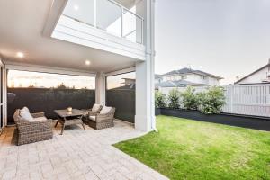 a patio with a table and chairs and a lawn at Fernweh - A Generous Hamptons-style Beachside Escape in Geographe