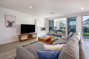 a living room with a couch and a flat screen tv at Fernweh - A Generous Hamptons-style Beachside Escape in Geographe
